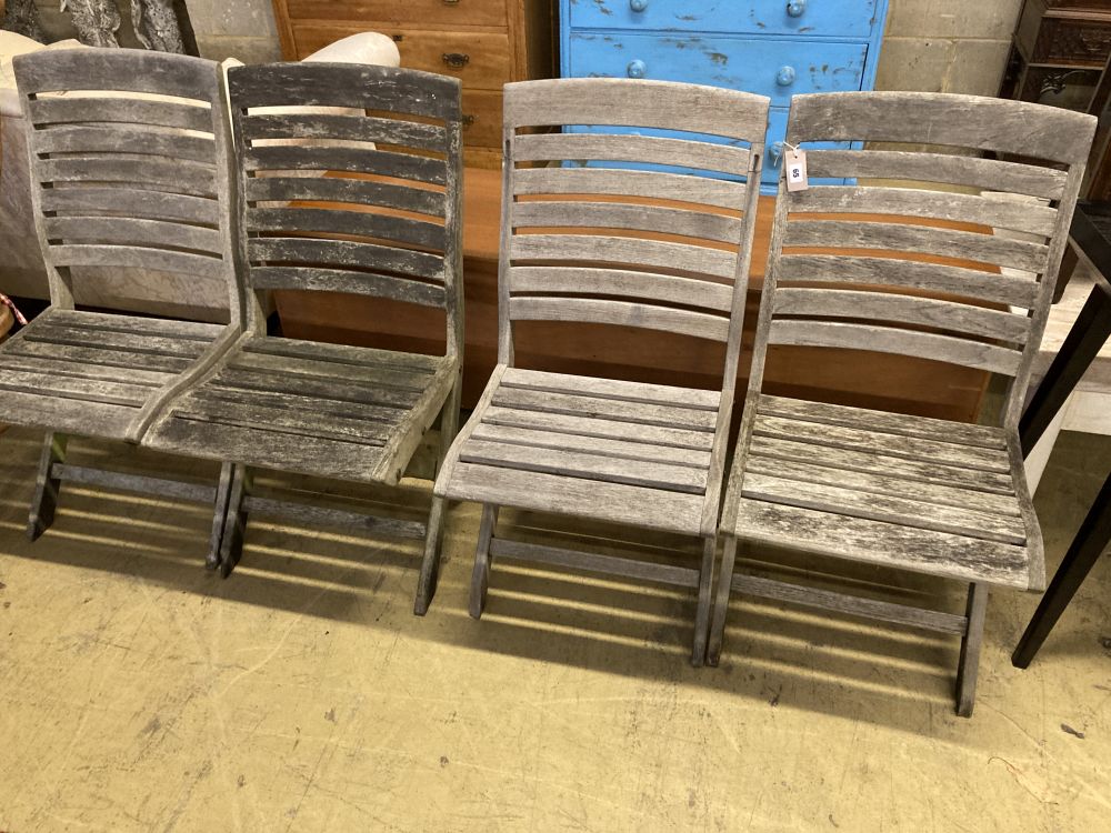 A set of four weathered teak folding garden chairs